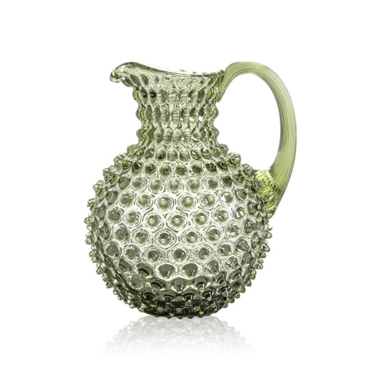 Green glass pitcher with textured surface on a white background