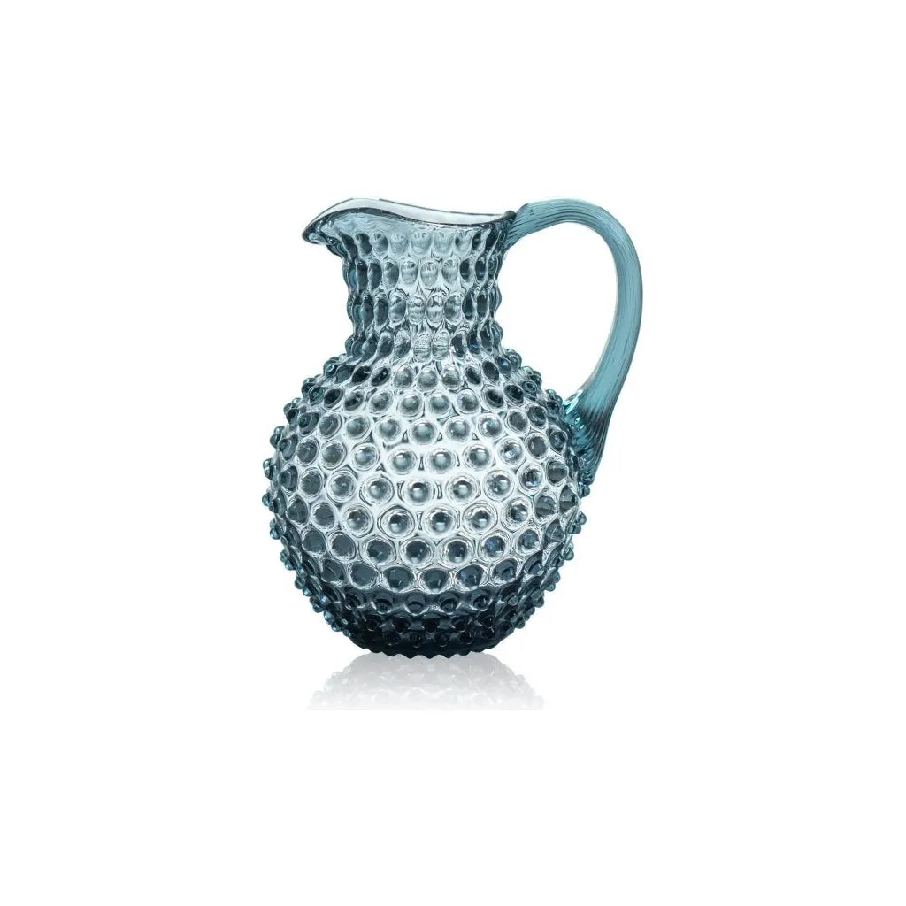 Blue glass pitcher with textured surface on a white background