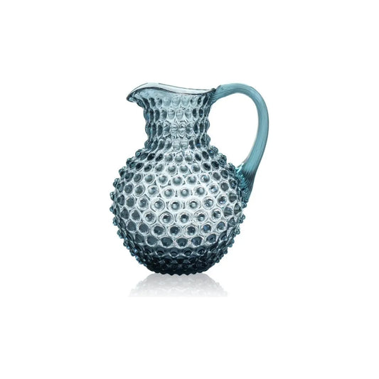 Blue glass pitcher with textured surface on a white background