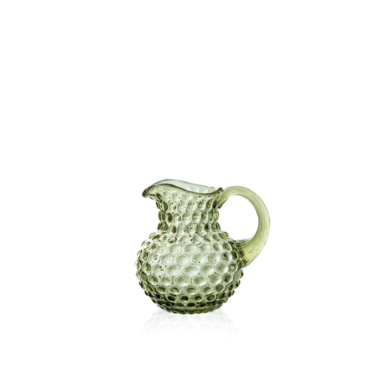Green glass pitcher with textured surface on a white background